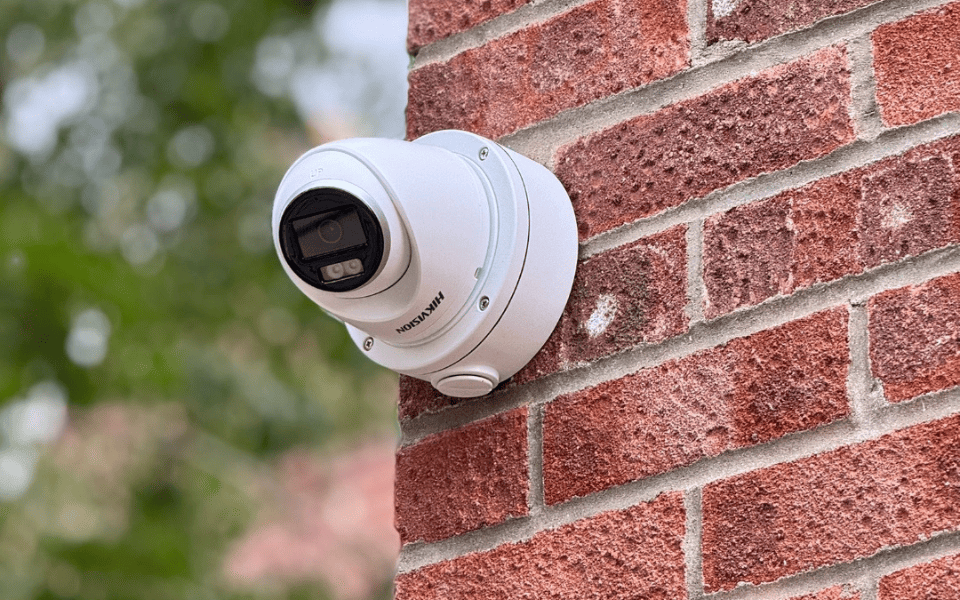 Navy and white dome CCTV camera with a secured checkmark badge